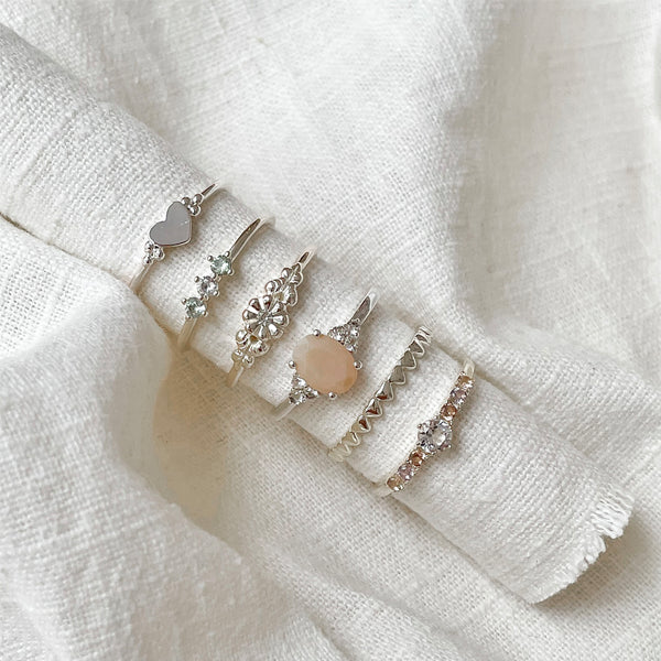 Elegant stack of rings from 24KAE JEWELS JEWELRY Mod. 12418S/52 collection on a soft fabric background.