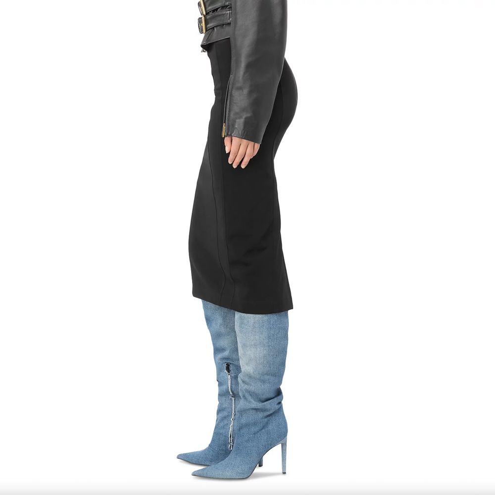 Side view of a model wearing a PINKO Black Viscose Skirt, slim fit with rear slit, paired with denim boots and leather jacket.