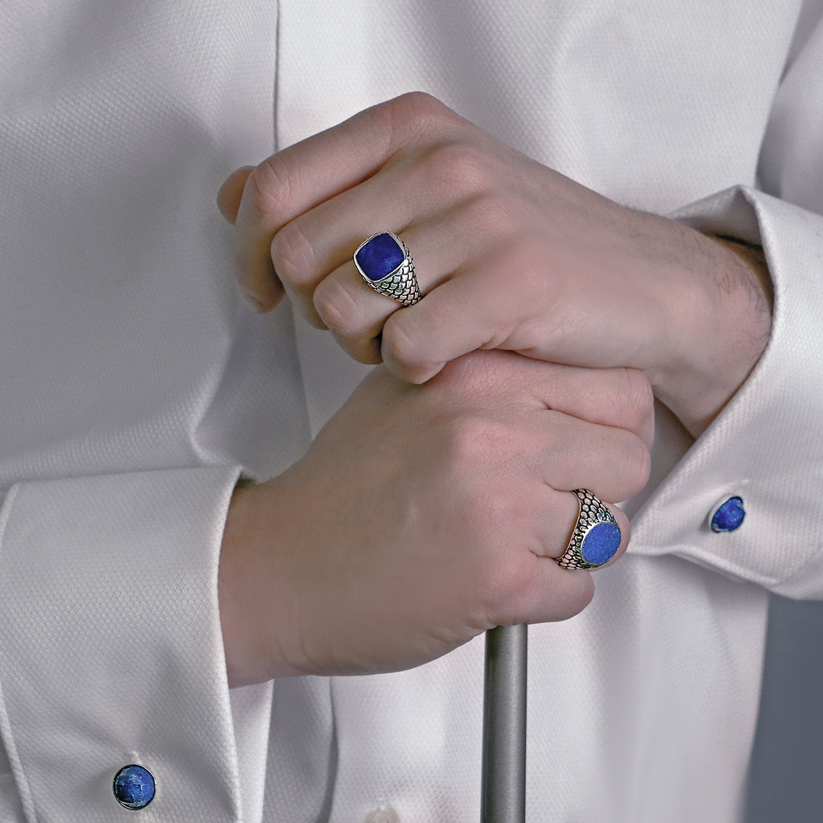 Close-up of hands wearing ALBERT M. JEWELS JEWELRY Mod. WSOX00174.TRQ rings and cufflinks on a white shirt.