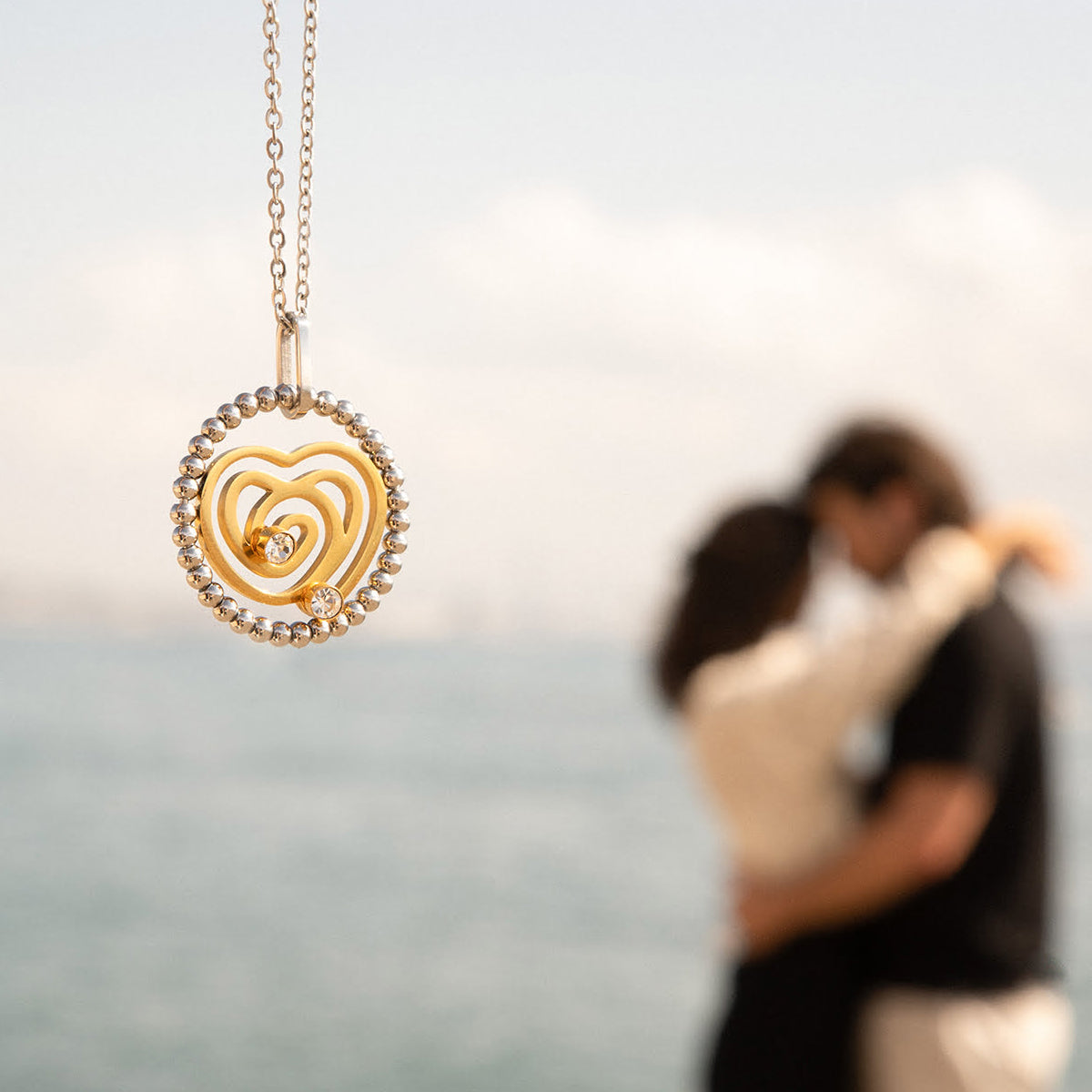 AN JEWELS JEWELRY Mod. AL.NSOKLSYC gold heart pendant with couple embracing by the sea in the background.