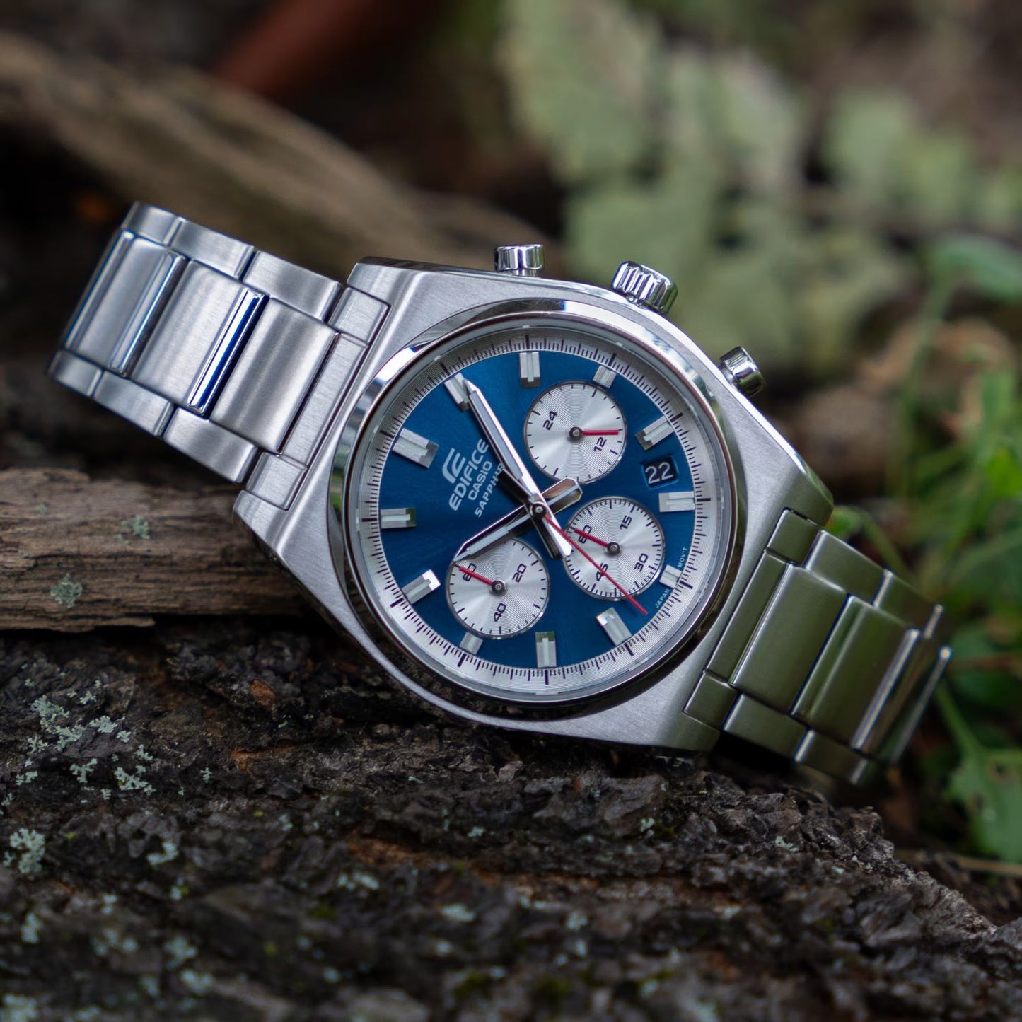 CASIO EDIFICE Mod. MOTORSPORT CHRONOGRAPH BLUE wristwatch with stainless steel band and sapphire dial, lying on a rock.