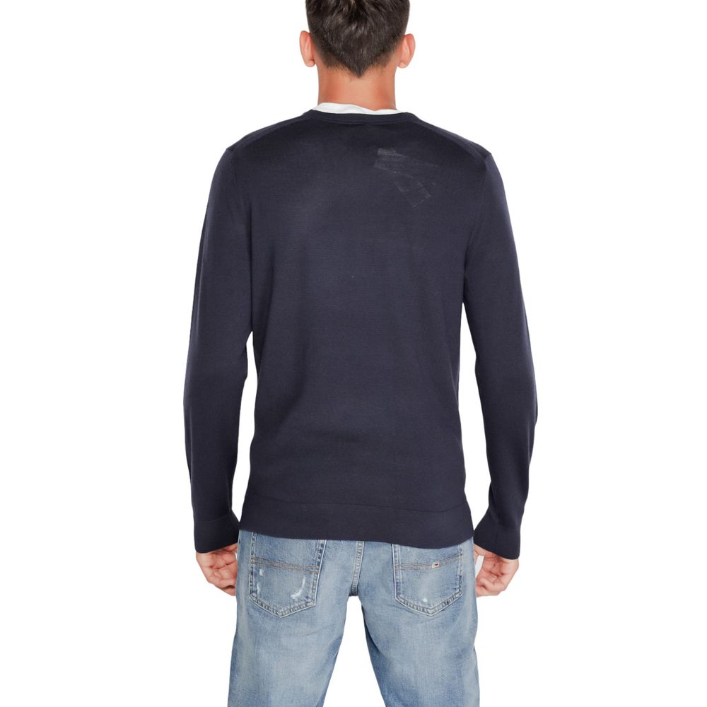 Back view of a man wearing a Calvin Klein Blue Recycled Wool Sweatshirt with denim jeans, showcasing a stylish and sustainable fashion choice.