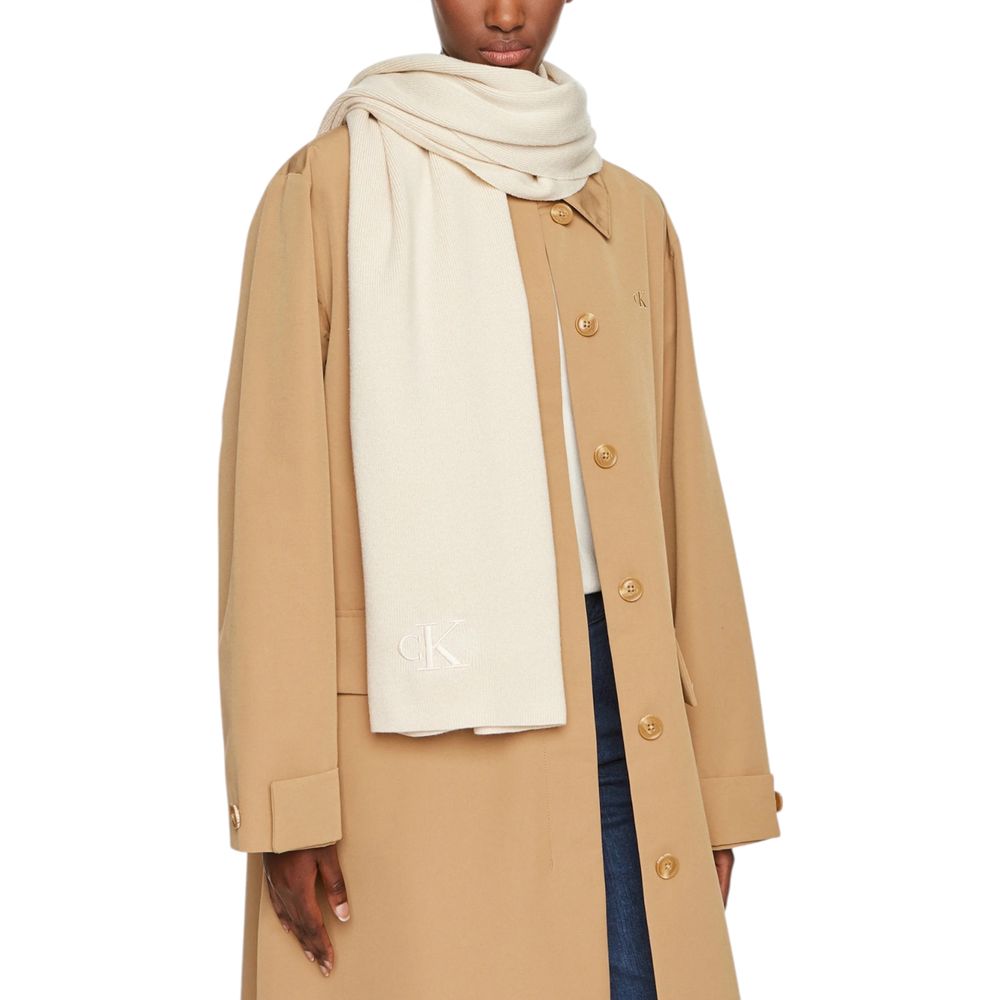 Woman wearing Calvin Klein Cream Recycled Polyester Scarf with coat, showcasing monogram embroidery.