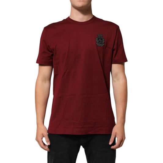 Man wearing Dolce & Gabbana Bordeaux Red Cotton Crest Logo Patch T-Shirt with short sleeves and crew neck, showcasing black embroidered crest.