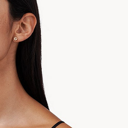 Elegant woman wearing small heart-shaped stud earring on earlobe