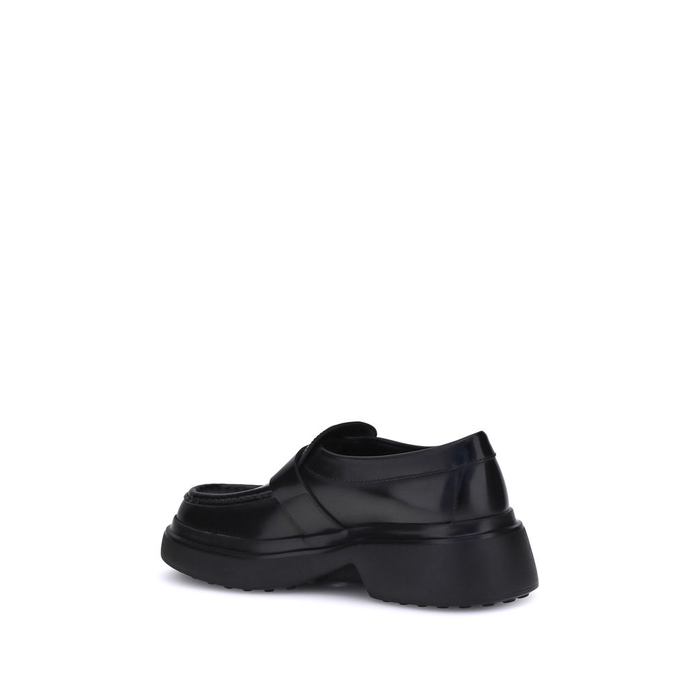 Rear view of Tod's Black Rubber Platform Loafers with nappa leather upper and metal ring embellishments on a platform sole.